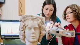 古天乐代言太阳集团的教授和她的学生正在检查一座古代的半身像雕塑.